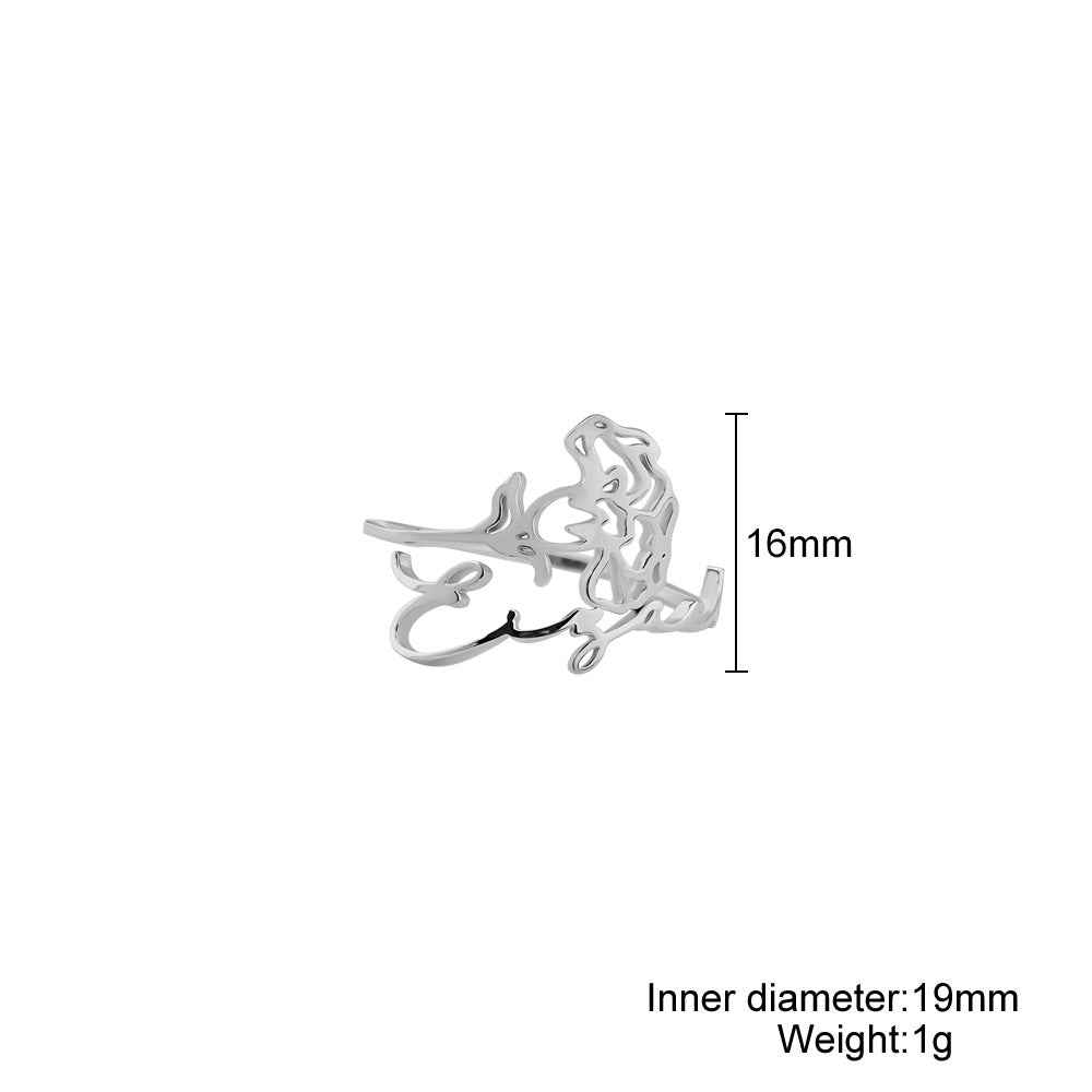 A stainless steel ring with a floral design, placed on a silky fabric surface.