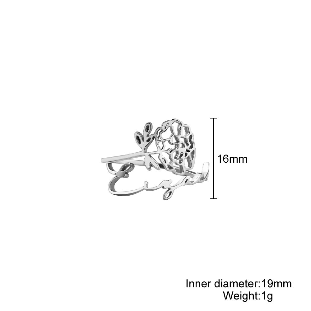 A stainless steel ring with a floral design, placed on a silky fabric surface.