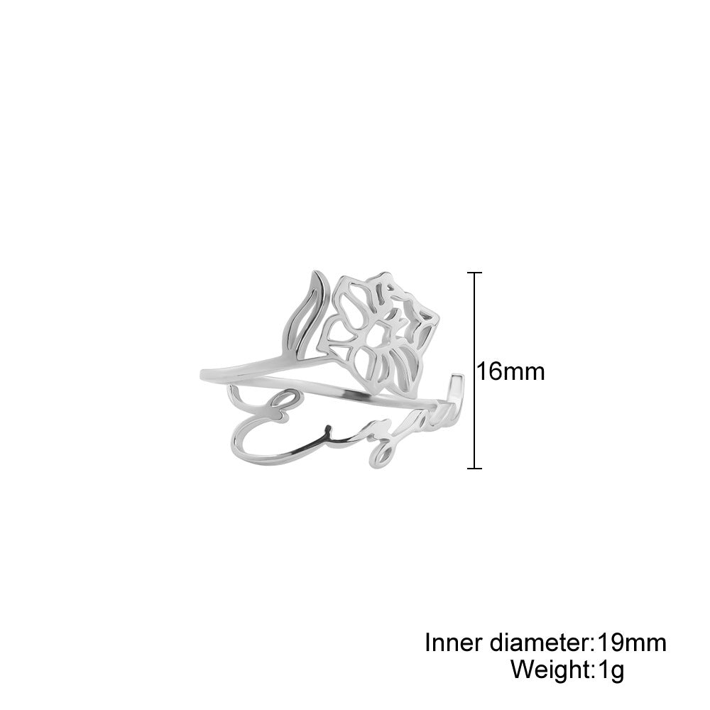 A stainless steel ring with a floral design, placed on a silky fabric surface.