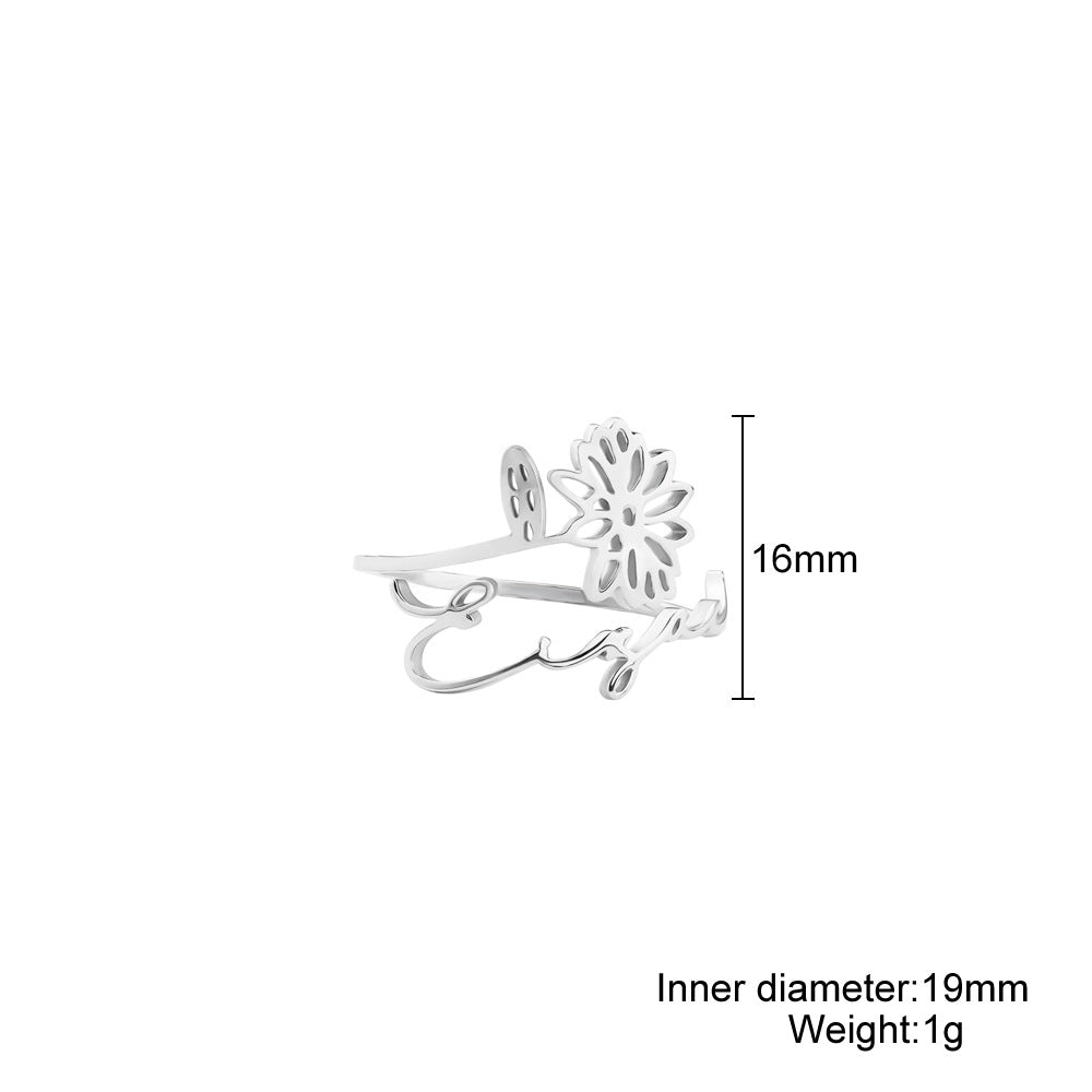 A stainless steel ring with a floral design, placed on a silky fabric surface.