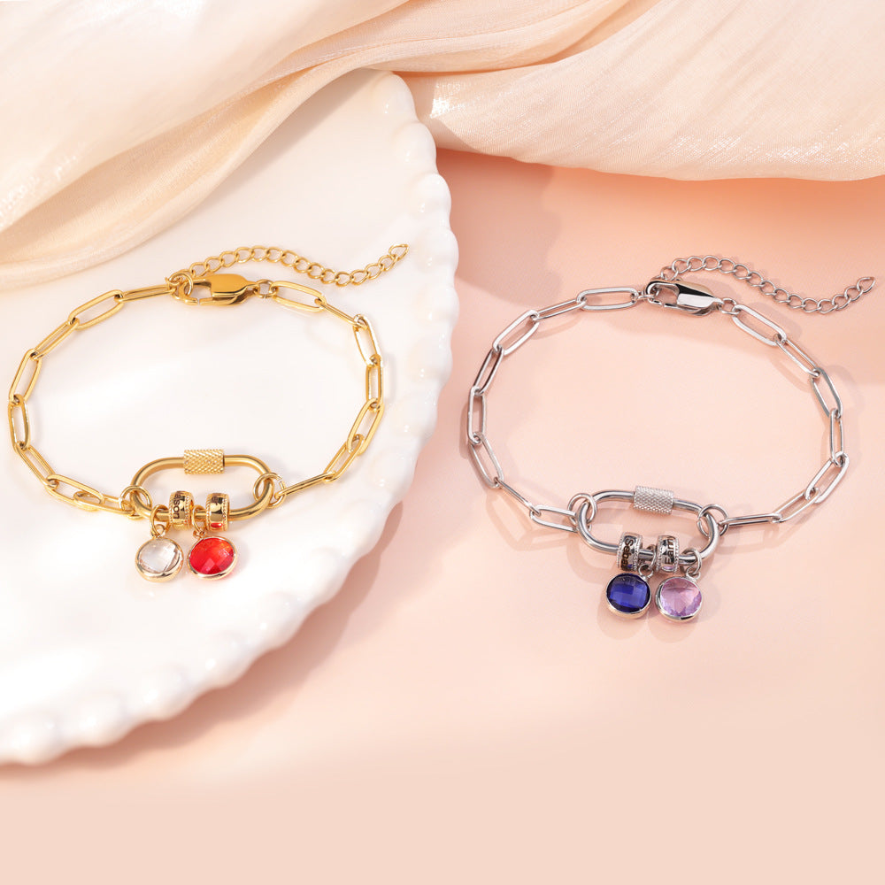 A two-part jewelry set with a pendant and a bracelet, featuring colorful gemstones and metallic clasps, displayed on a surface with pink crystals.