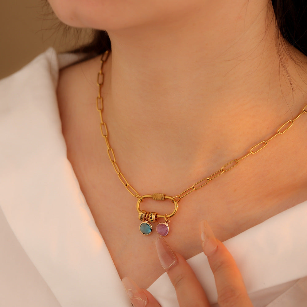 A two-part jewelry set with a pendant and a bracelet, featuring colorful gemstones and metallic clasps, displayed on a surface with pink crystals.
