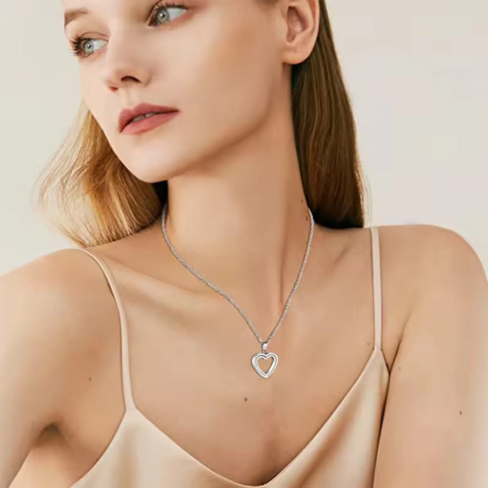 Woman wearing a silver heart-shaped necklace against a neutral background