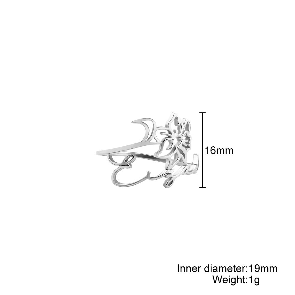 A stainless steel ring with a floral design, placed on a silky fabric surface.