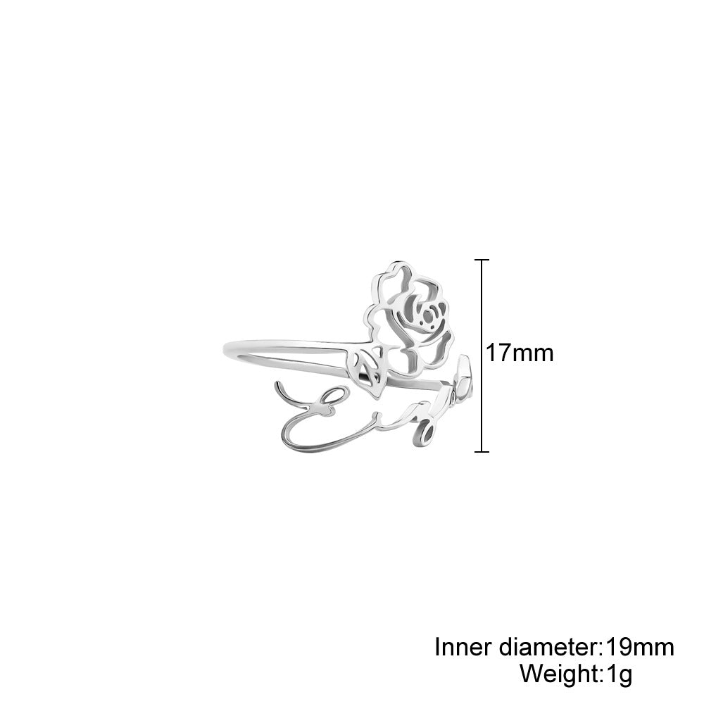 A stainless steel ring with a floral design, placed on a silky fabric surface.