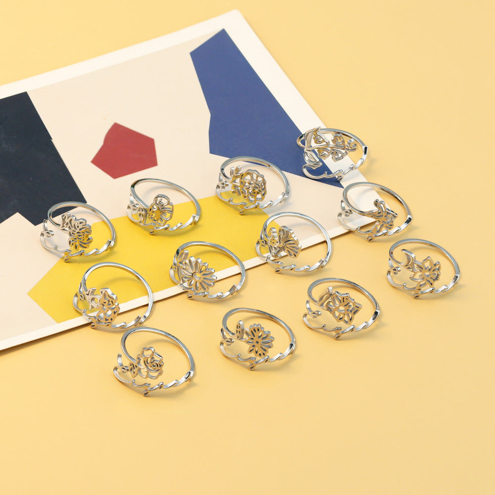 A stainless steel ring with a floral design, placed on a silky fabric surface.