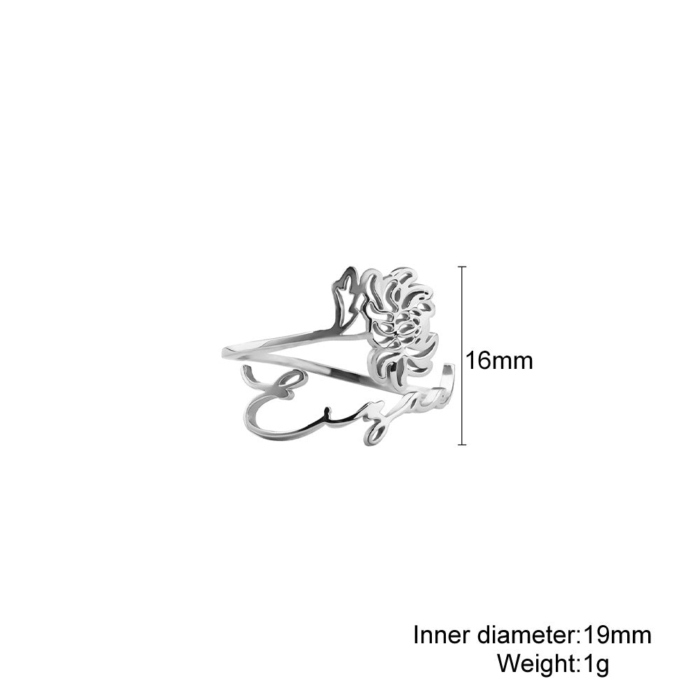 A stainless steel ring with a floral design, placed on a silky fabric surface.