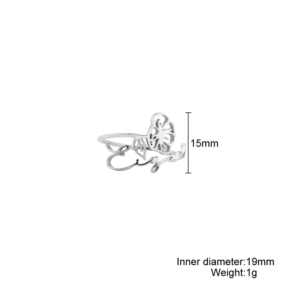 A stainless steel ring with a floral design, placed on a silky fabric surface.