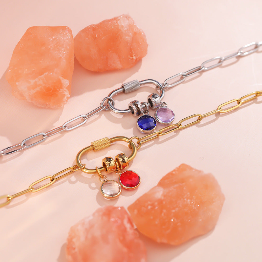 A two-part jewelry set with a pendant and a bracelet, featuring colorful gemstones and metallic clasps, displayed on a surface with pink crystals.