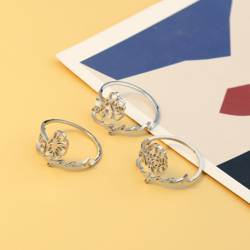 A stainless steel ring with a floral design, placed on a silky fabric surface.