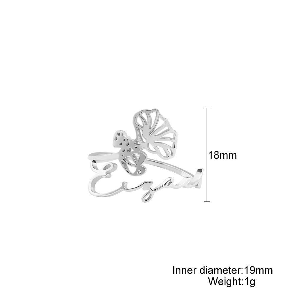 A stainless steel ring with a floral design, placed on a silky fabric surface.