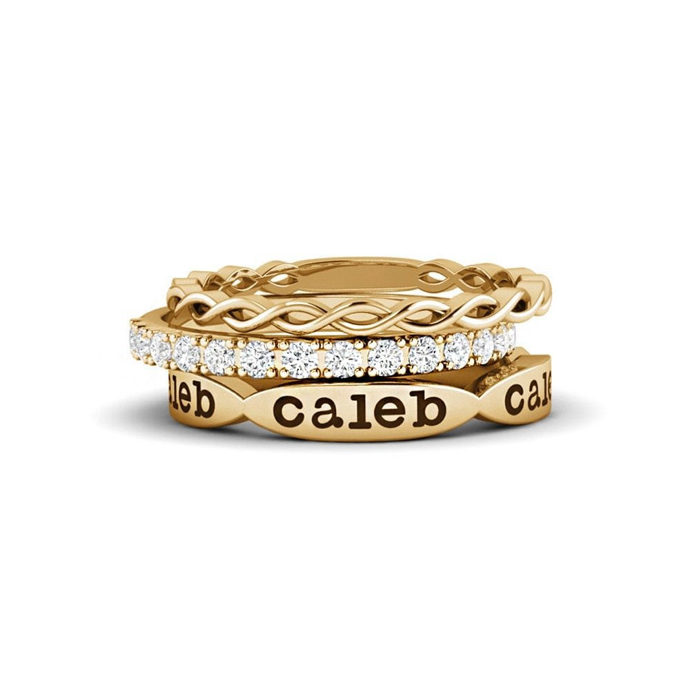 A gold-colored ring with multiple bands and a personalized engraving of a name on the top band.