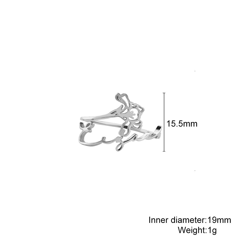 A stainless steel ring with a floral design, placed on a silky fabric surface.