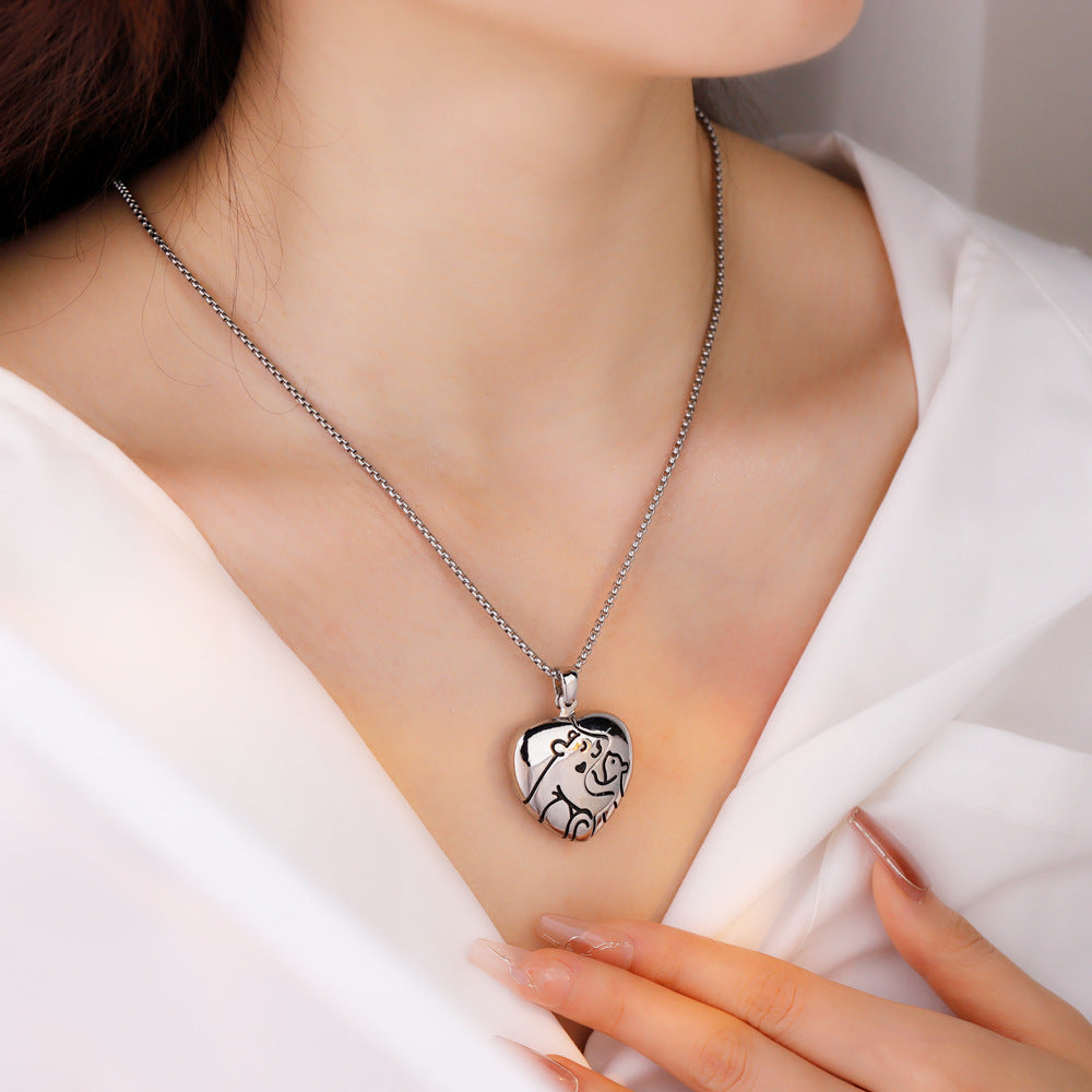 A person wearing a silver necklace with a custom-made pendant in the shape of a bear hug, displayed on a white background.